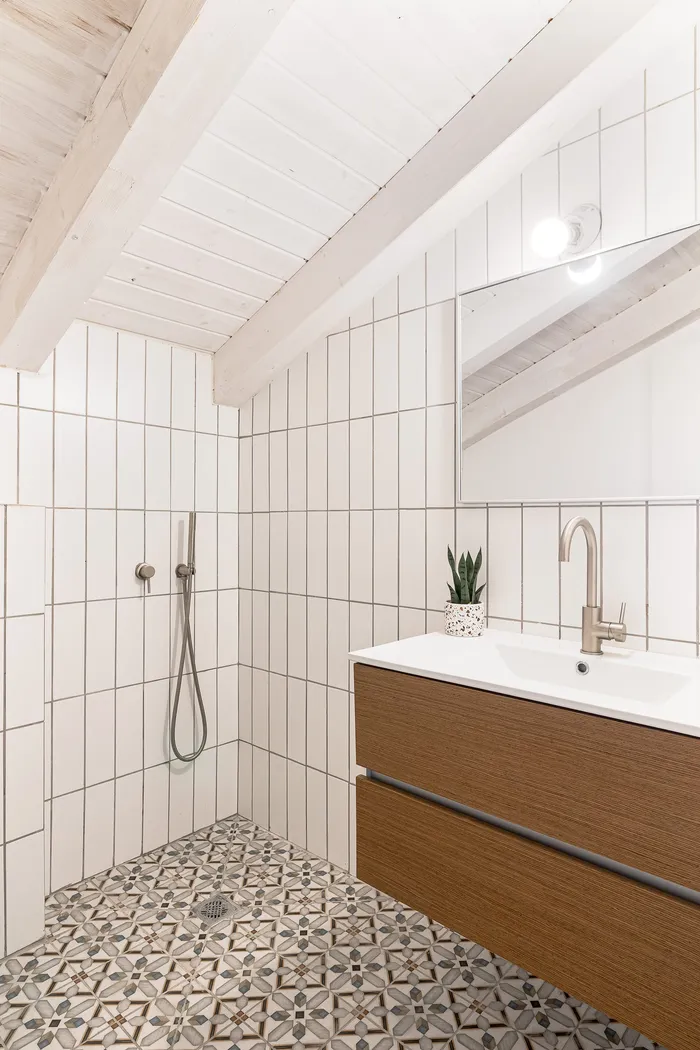 חדר רחצה תחת תקרה משופעת עם אריחים מעוטרים וארון עץ