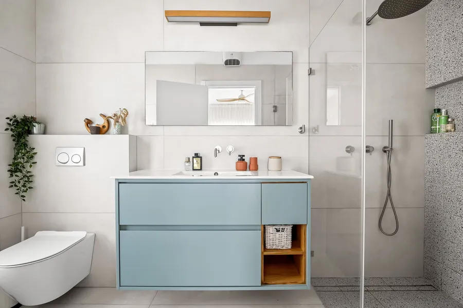 חדר רחצה עם ארון תכלת, אריחים לבנים וקיר טרצו במקלחת