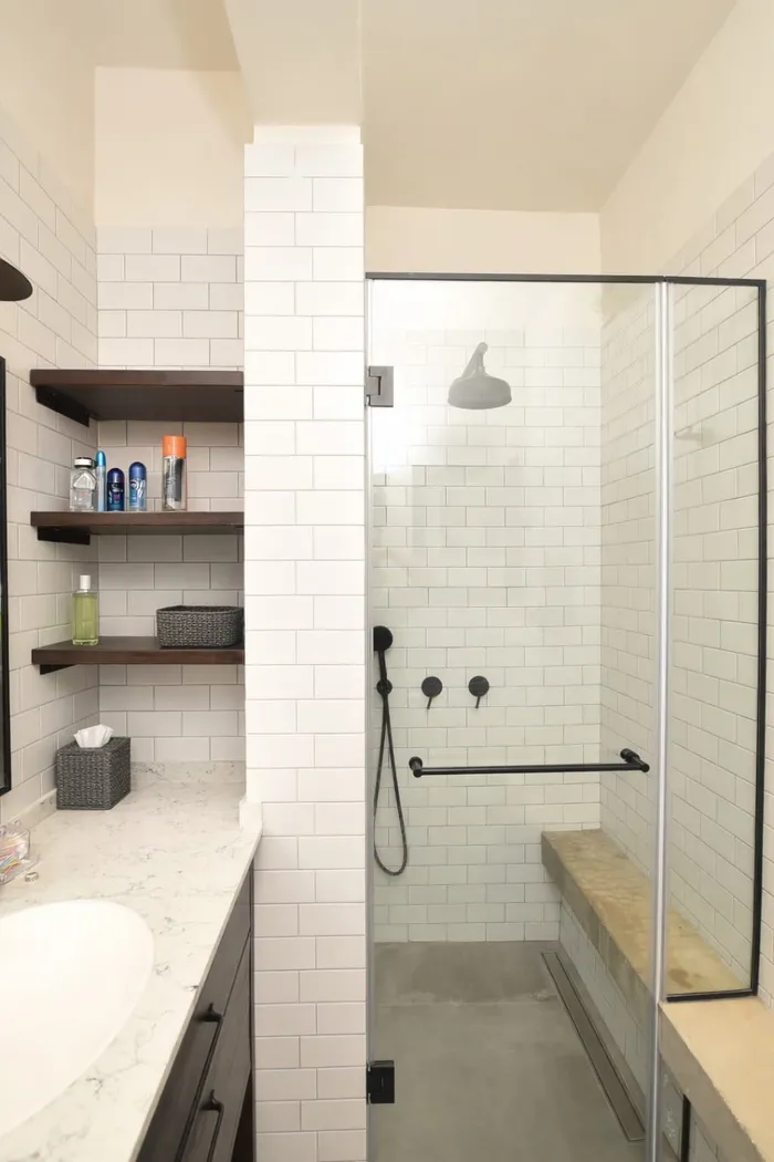 מקלחון עם אריחי סאבוויי לבנים, ברזים שחורים, מחיצת זכוכית ורצפת בטון