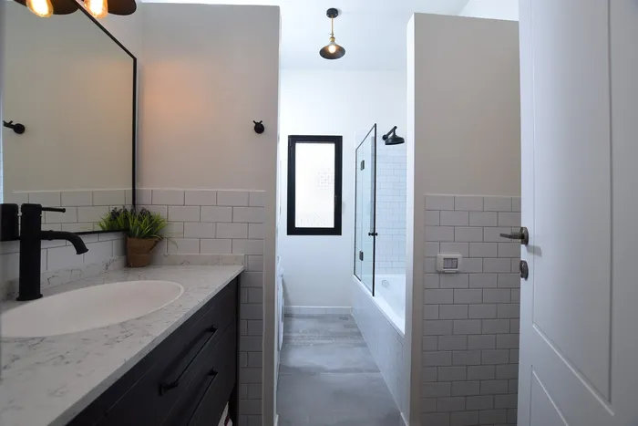 חדר רחצה עם אריחי סאבוויי לבנים, ברזים שחורים ומשטח שיש