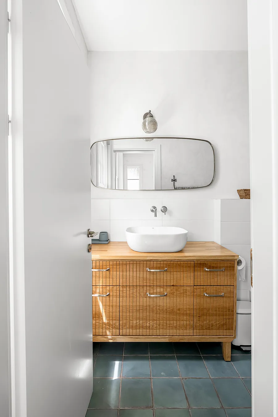 חדר רחצה עם ארון אלון מחורץ ואריחים ירוקים