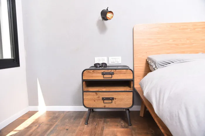 שידת צד מעץ ומתכת ליד מיטה עם ראש אלון, גוף תאורה תעשייתי ופרקט חם