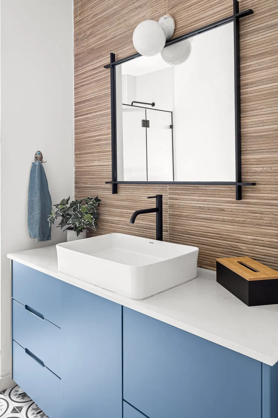 חדר רחצה עם ארון כחול, חיפוי עץ וברזים שחורים