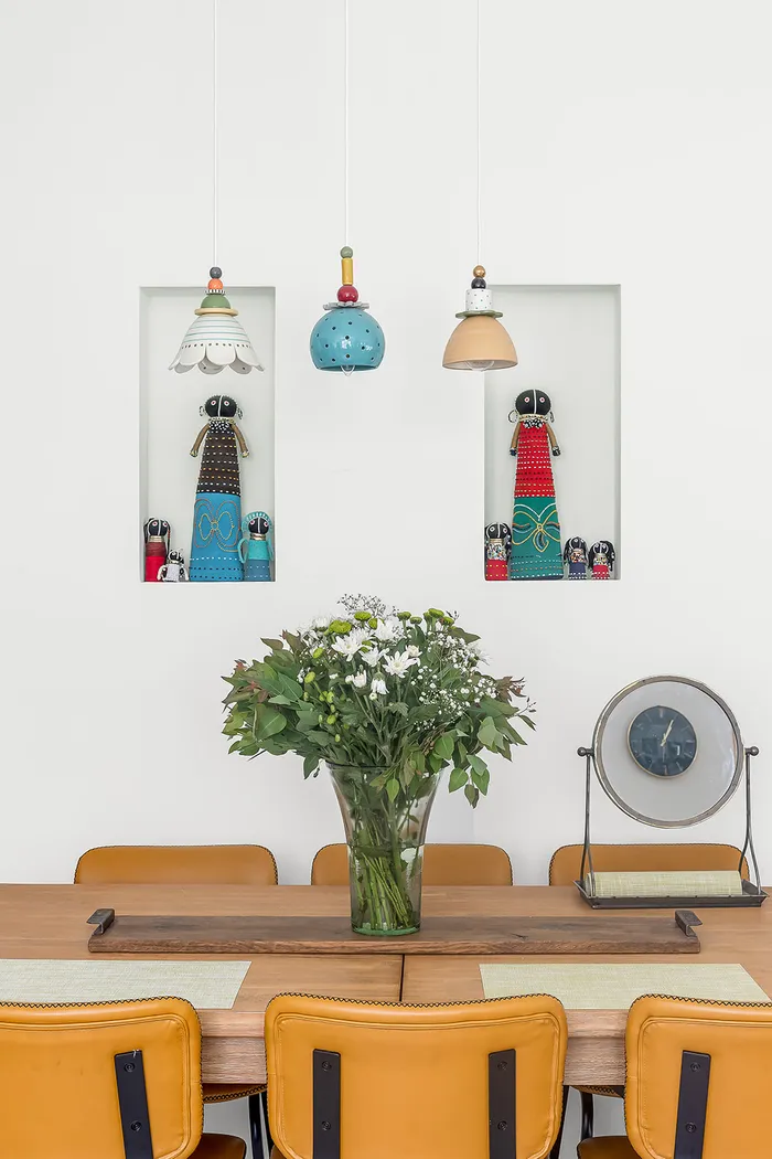 פינת אוכל עם כסאות צהובים, גופי תאורה צבעוניים ובובות אספנות