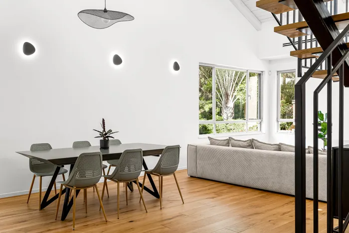 פינת אוכל עם גופי תאורה וגרם מדרגות מברזל שחור