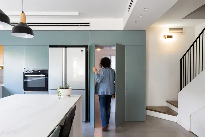 דלת סמויה בקיר המטבח הטורקיז — מעבר חכם בין החללים