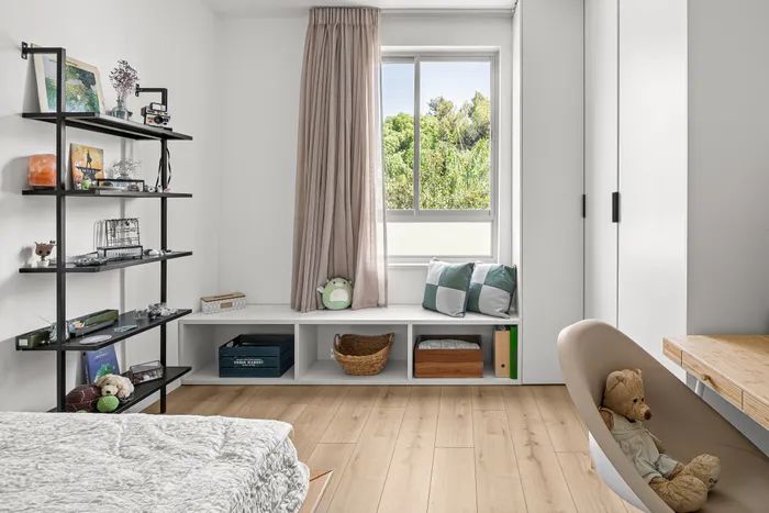 חדר ילדים עם מדפי ברזל שחור, ספסל חלון ואחסון פתוח