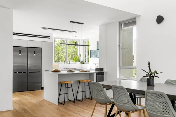 מטבח עם אי אפור וכסאות בר אלון, נוף ירוק מהחלון