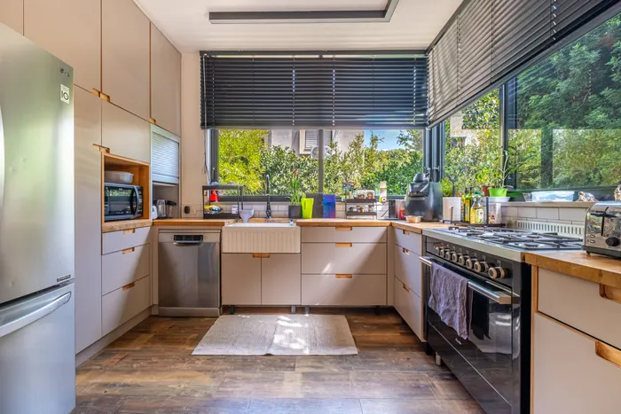 מטבח עם משטחי עץ, נגרות בהירה ואור טבעי מהחלונות