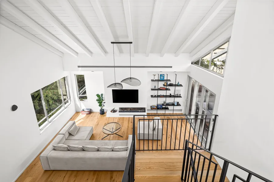 מבט מהגלריה אל הסלון — תקרת קורות, קמין וריצוף אלון