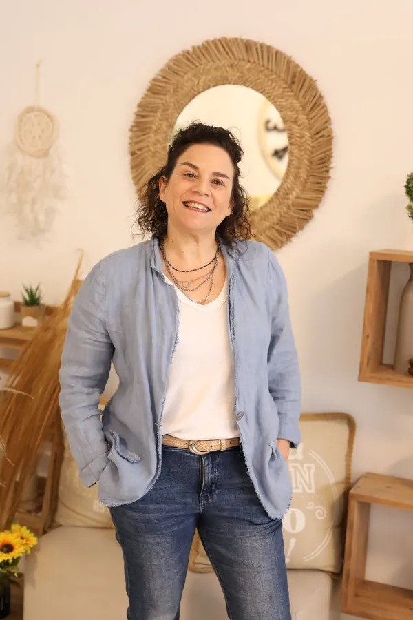 אסתי גכטמן כהן יושבת בסטודיו עם חיוך חם
