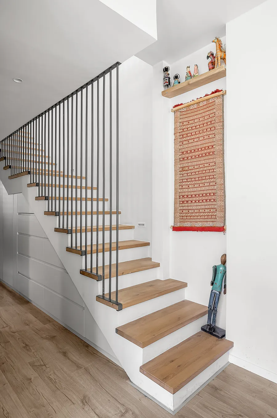 גרם מדרגות עם מדרכי אלון, שטיח ארוג ופסלונים אספניים