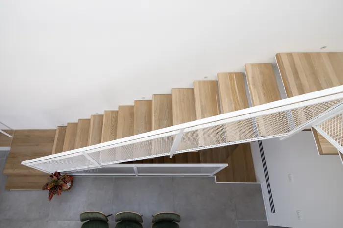 מדרגות אלון מרחפות עם מעקה רשת לבן — מבט מלמעלה