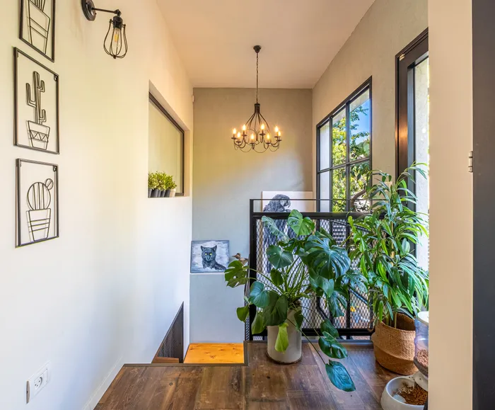 חלל מדרגות עם מעקה ברזל, צמחייה ונברשת תעשייתית