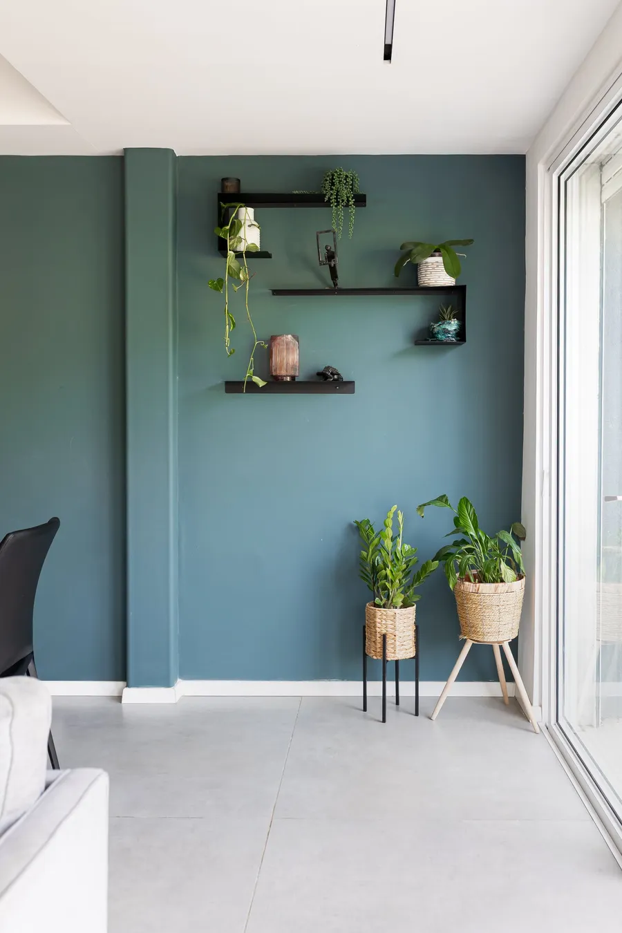 קיר טורקיז עם מדפים שחורים, צמחים ואקססוריז