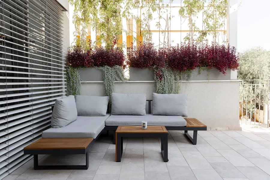 מרפסת עם פינת ישיבה וצמחייה נשפכת