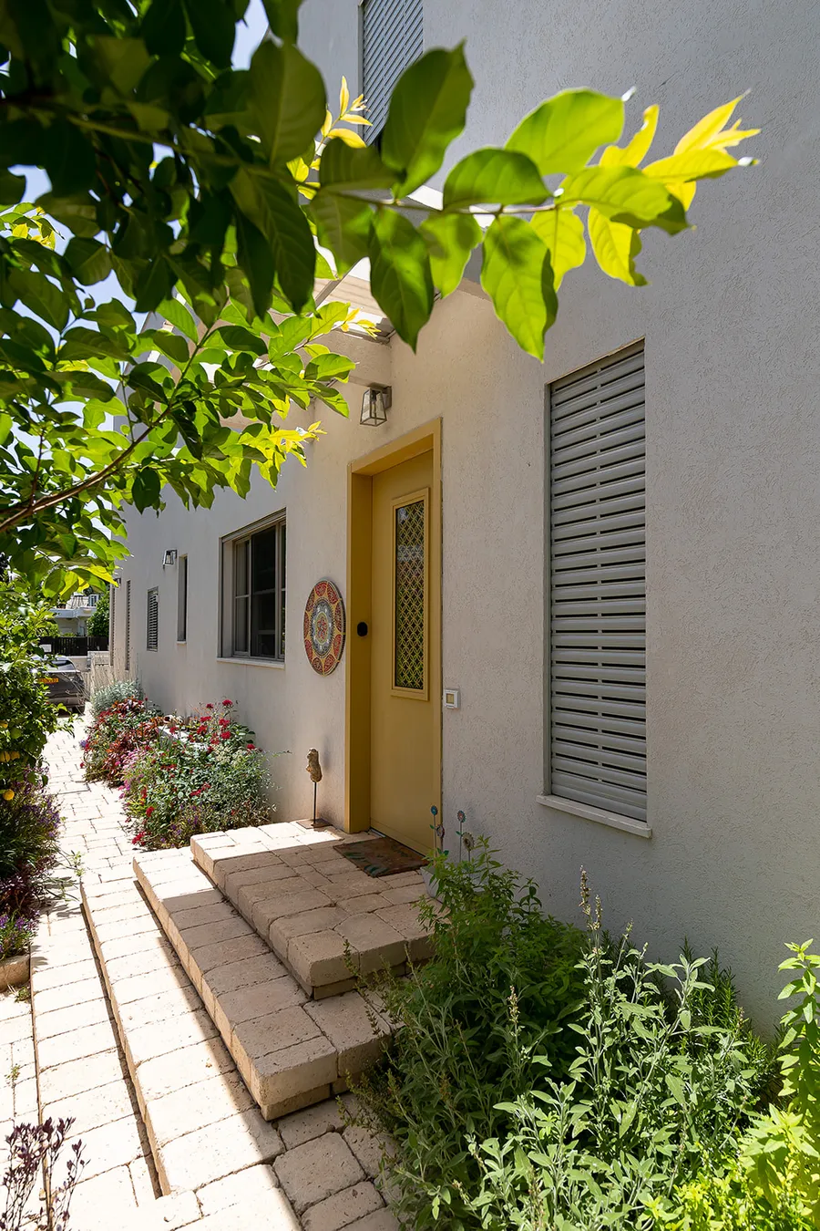 כניסה לבית עם דלת צהובה, קרמיקה ושביל גינה